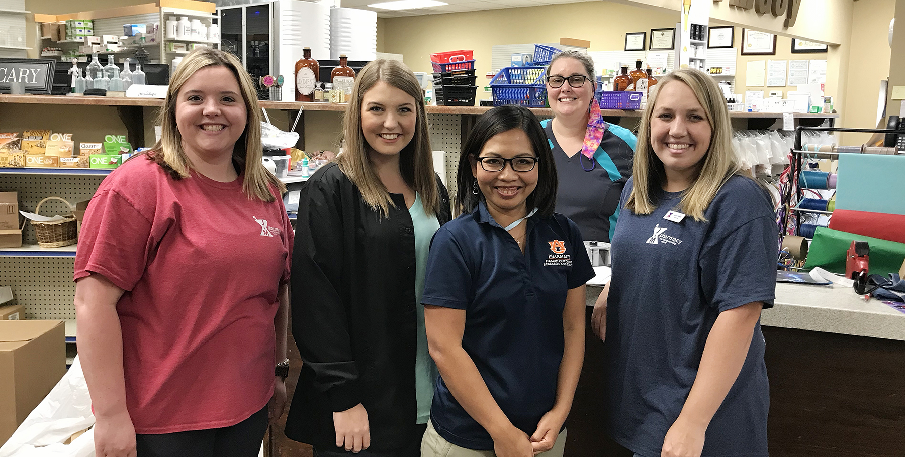 Group of five women stand in front of pharmacy counter