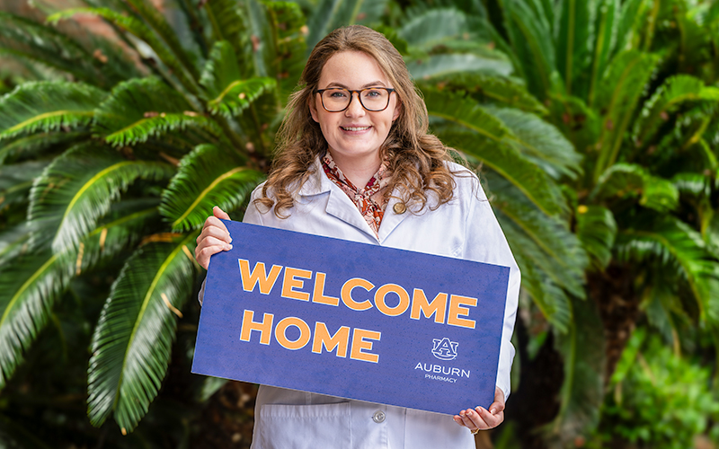 Smiling student holding a sign that says welcome home