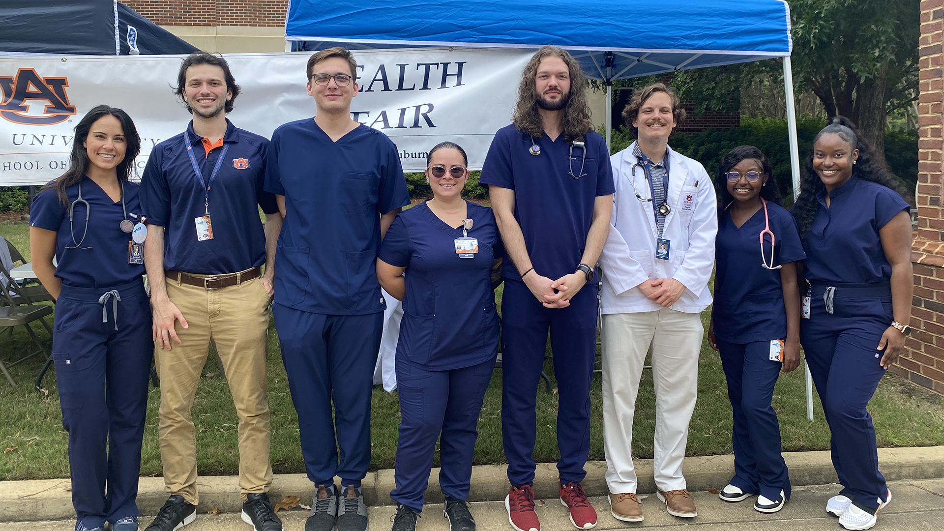Students stand in front of tent at health fair