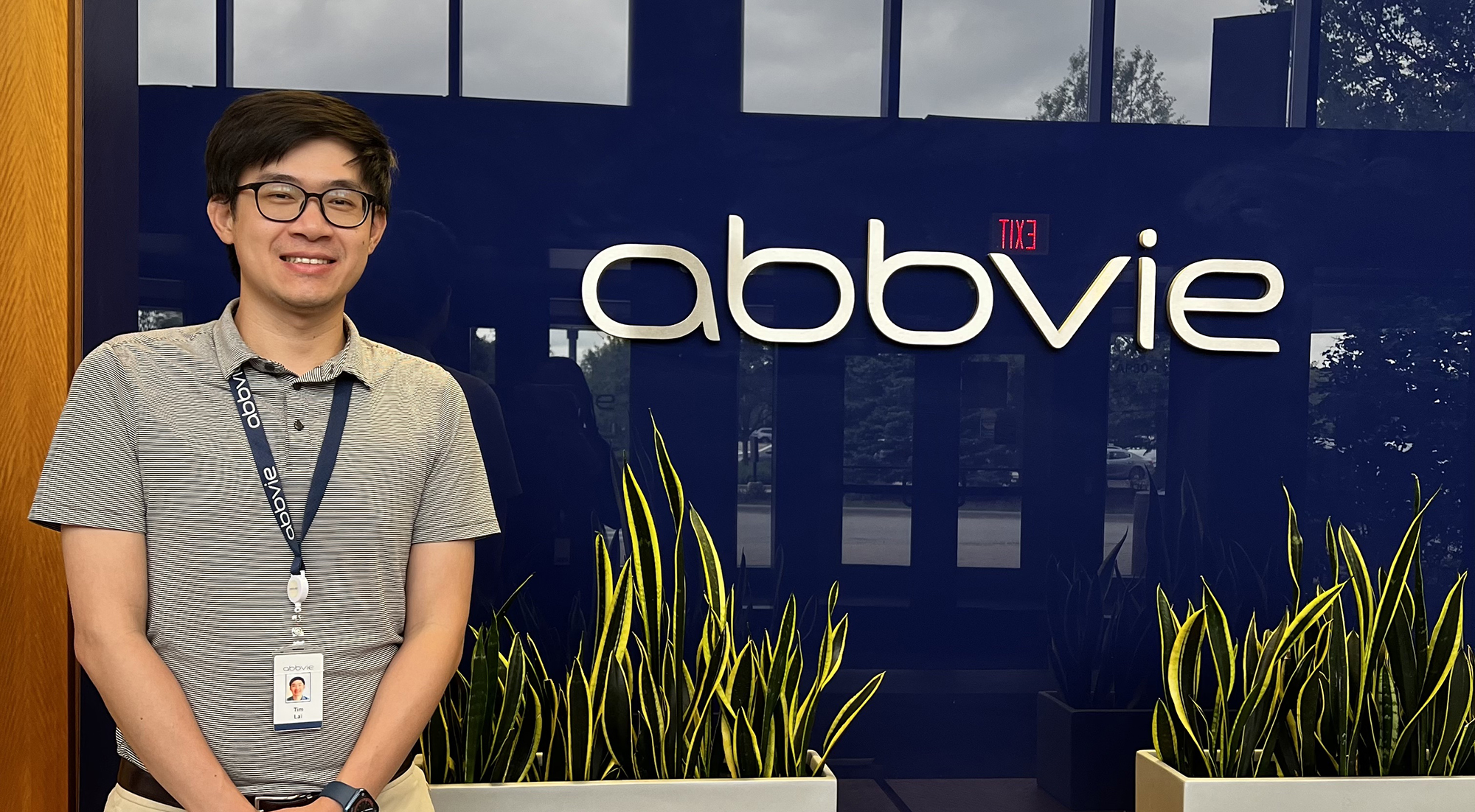Tim Lai stands next to sign